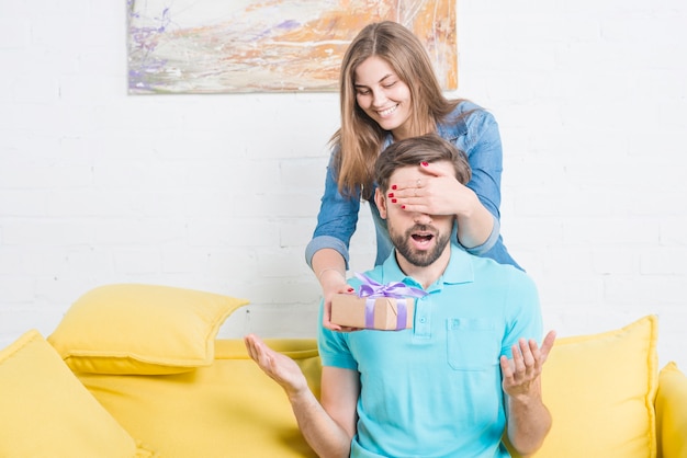 Vrouw die de ogen van haar vriend behandelen die hem valentijnskaartgift geven