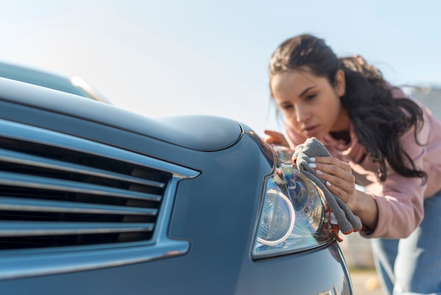 Gratis foto vrouw die de voorzijde van de auto schoonmaakt