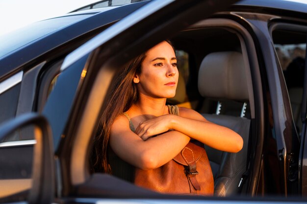 Vrouw die de zonsondergang bewondert vanuit de stoel van haar auto