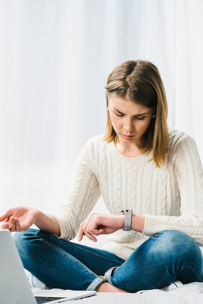 Vrouw die dichtbij laptop horloge bekijkt