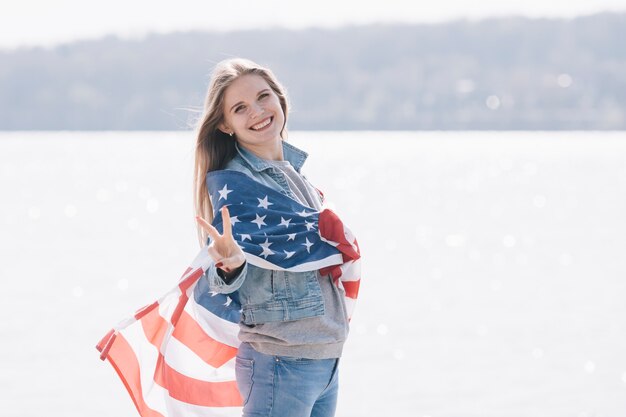 Vrouw die die en camera glimlacht bekijkt in Amerikaanse vlag wordt verpakt