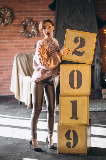 Gratis foto vrouw die door dozen 2019 op kerstmis bevindt zich