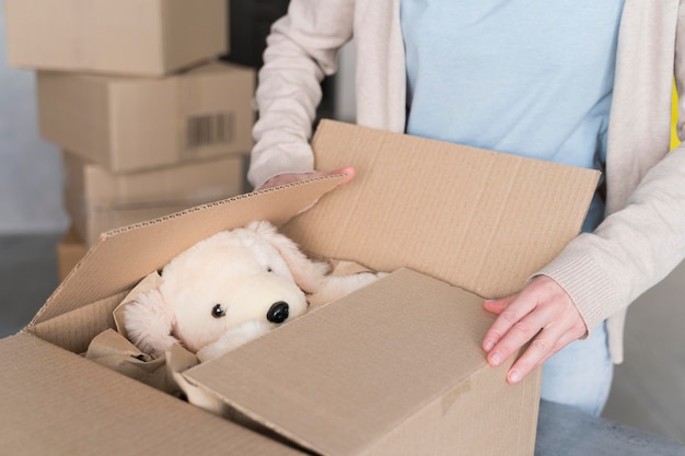 Vrouw die doos met te verzenden teddybeer voorbereidt