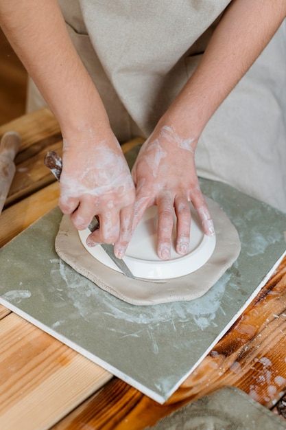 Vrouw die een aarden pot in haar atelier maakt