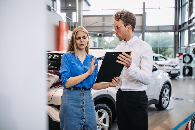 Vrouw die een auto in een autotoonzaal kiest