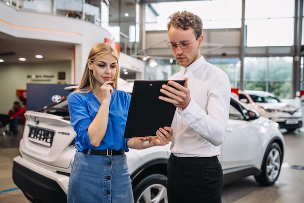 Vrouw die een auto in een autotoonzaal kiest