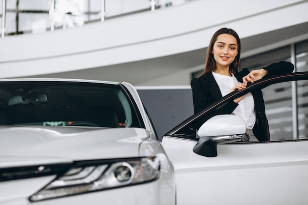 Vrouw die een auto in een autotoonzaal kiest