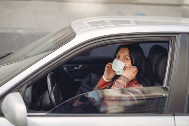 Vrouw die een beschermende maskerzitting in een auto draagt