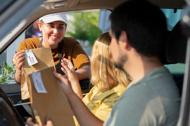 Gratis foto vrouw die een bestelling geeft bij een pick-up langs de stoep in de buitenlucht