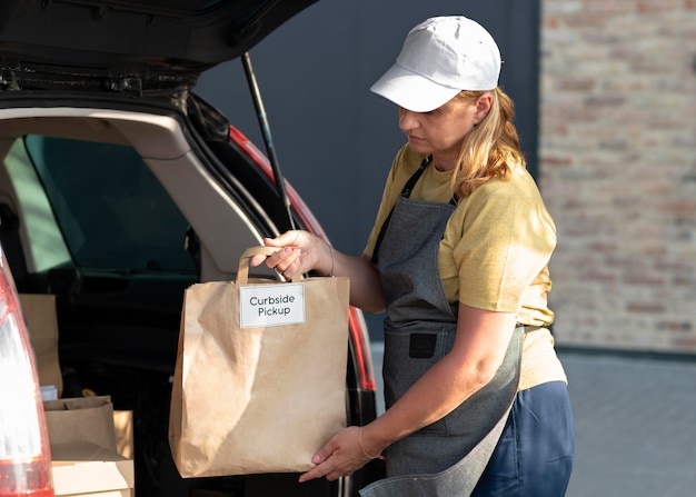 Vrouw die een bestelling geeft bij een pick-up langs de stoep in de buitenlucht