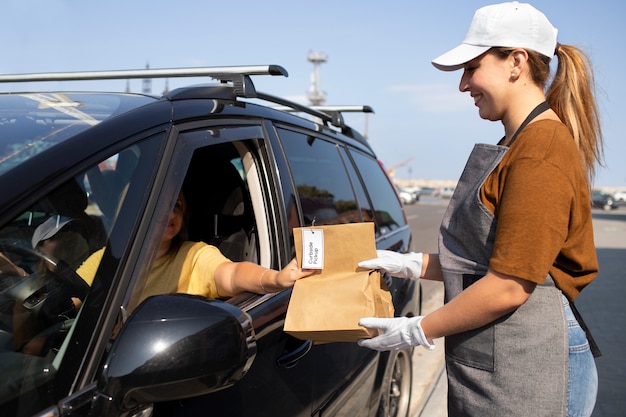 Gratis foto vrouw die een bestelling geeft bij een pick-up langs de stoep in de buitenlucht