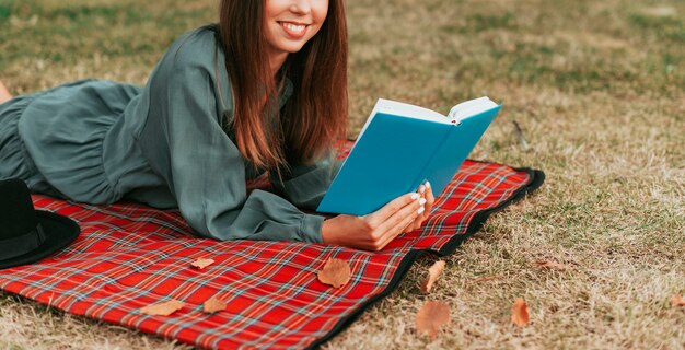 Vrouw die een boek op een picknickkleed leest met exemplaarruimte