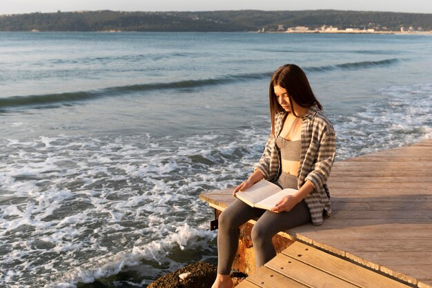 Vrouw die een boek op het strand leest