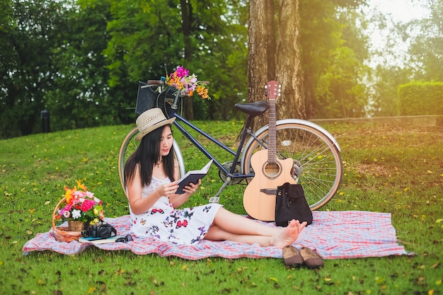 Vrouw die een boek over het ontspannen van tijd leest. de aziatische dame heeft picknick in openbaar park op vakantie