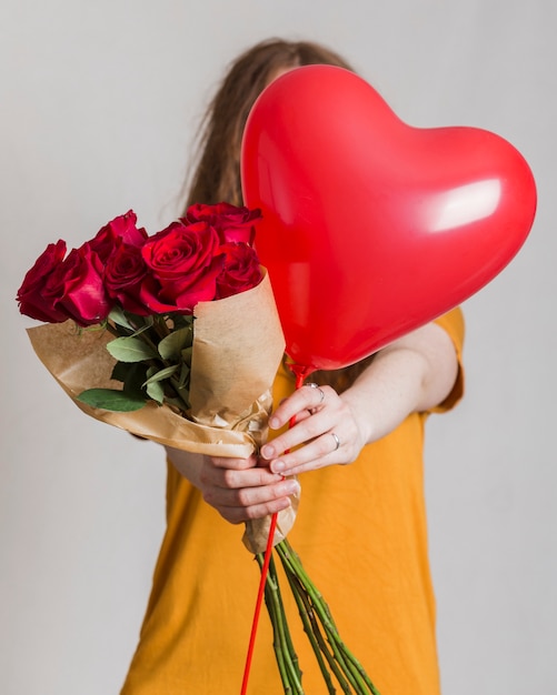 Vrouw die een boeket rozen en een ballon aanbiedt