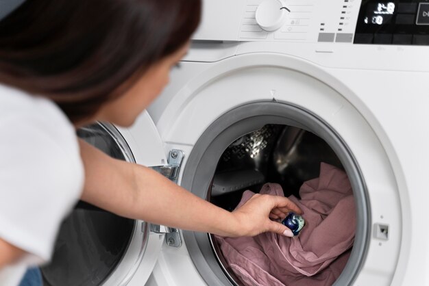 Vrouw die een capsule gebruikt om haar kleren te wassen