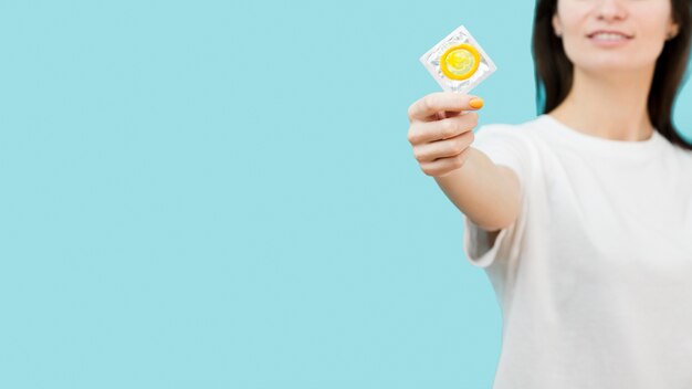 Vrouw die een geel condoom met exemplaarruimte steunt