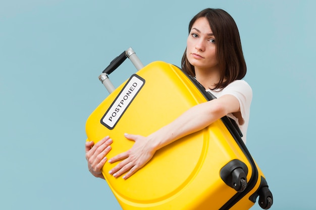 Vrouw die een gele bagage met een uitgesteld teken