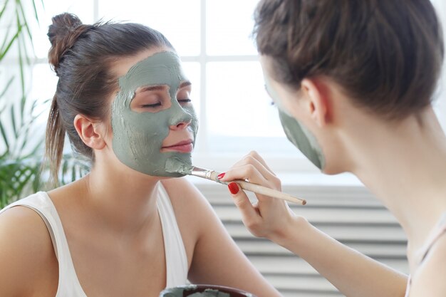 Vrouw die een gezichtsmasker toepast op haar vriend