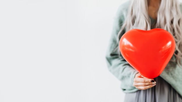 Gratis foto vrouw die een hartrode ballon toont