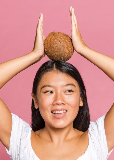 Vrouw die een kokosnoot op haar hoofd houdt