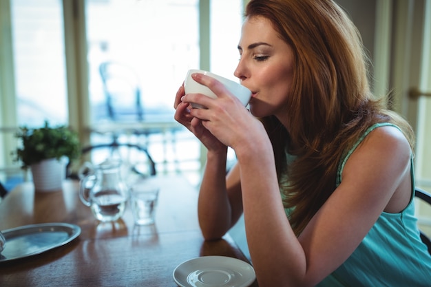 Gratis foto vrouw die een kopje koffie in cafã ©