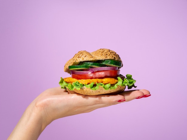 Vrouw die een smakelijke hamburger in haar palm houdt