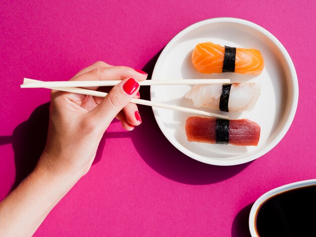 Vrouw die een sushistuk met eetstokjes neemt