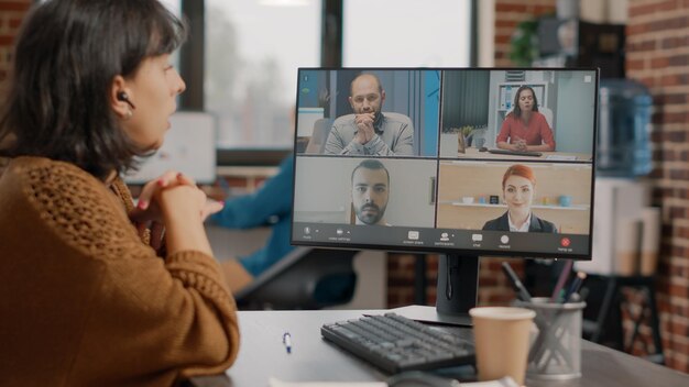 Vrouw die een zakelijke bijeenkomst bijwoont tijdens een videogesprek met collega's om te discussiëren over projectplanning en -strategie. Werknemer doet teamwerk met collega's op online videoconferentie.