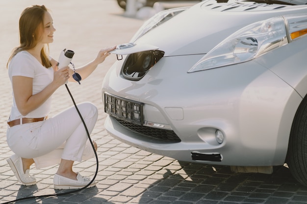 Vrouw die elektro auto laadt bij het elektrische benzinestation