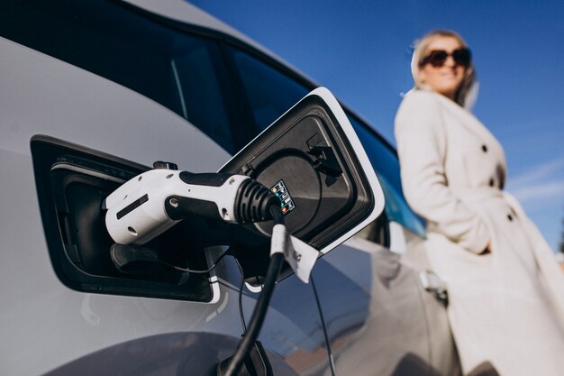 Vrouw die elektroauto laden door haar huis