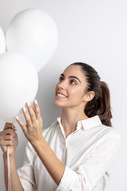 Vrouw die en ballons glimlacht houdt