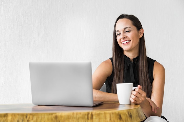 Vrouw die en haar laptop glimlacht controleert