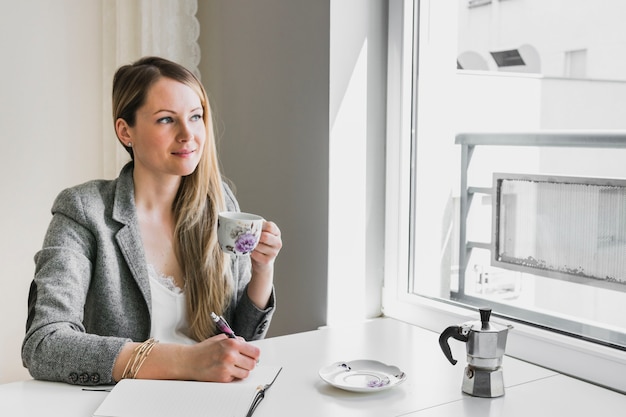 Gratis foto vrouw die en notities drinkt maakt