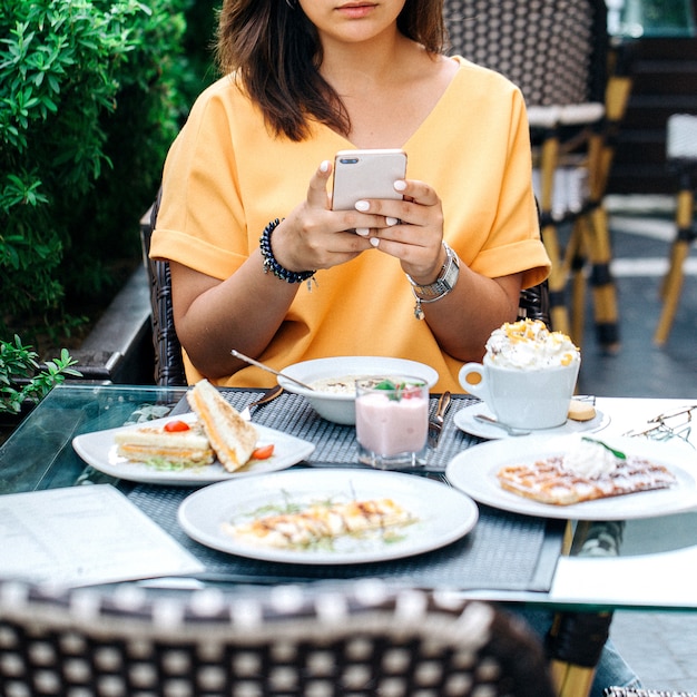 Gratis foto vrouw die foto van lijst met voedsel neemt