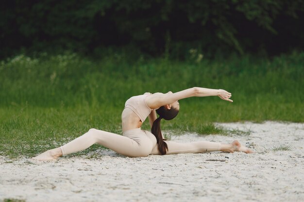 Vrouw die geavanceerde yoga in een strand uitoefenen