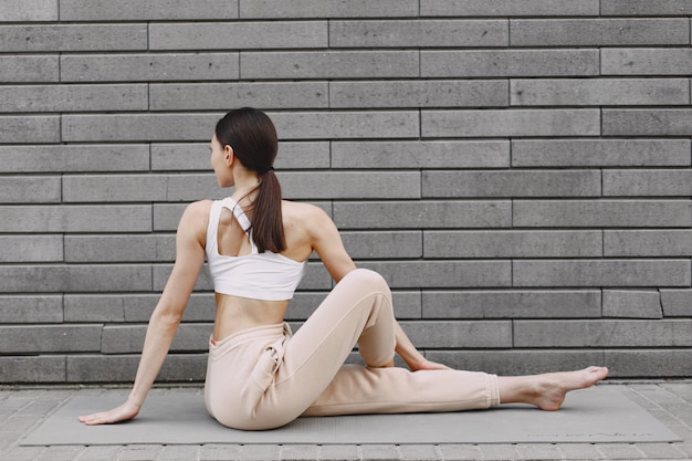 Vrouw die geavanceerde yoga uitoefenen tegen een donkere stedelijke muur