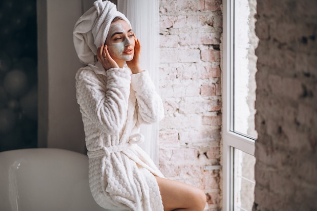 Vrouw die gezichtsmasker in een badkamers toepast