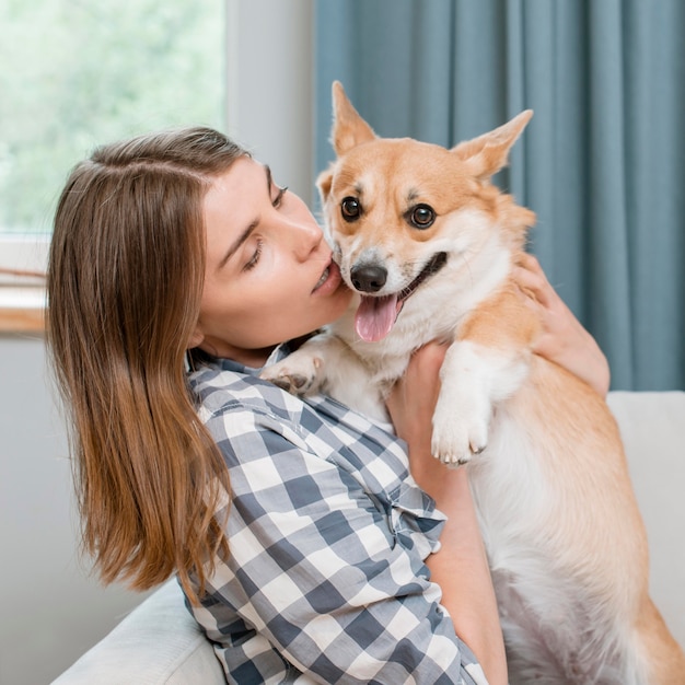 Gratis foto vrouw die haar aanbiddelijke huisdierenhond houdt