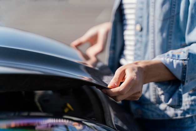 Vrouw die haar auto bekijkt om een probleem op te lossen