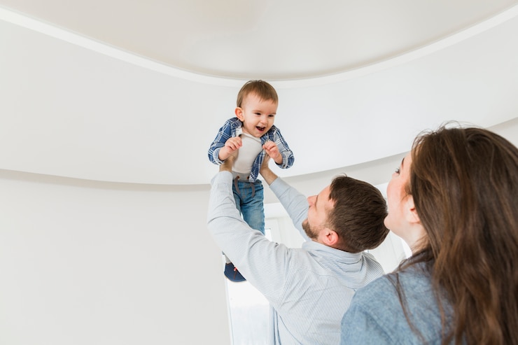 Gratis Foto vrouw die haar echtgenoot bekijkt die hun babyzoon in handen draagt