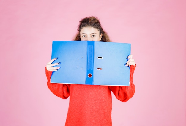 Gratis foto vrouw die haar gezicht bedekt met een blauwe map.