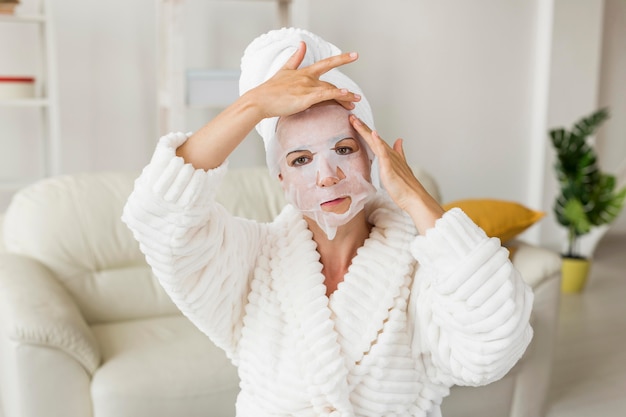 Vrouw die haar gezichtsmasker middelgroot schot toepast