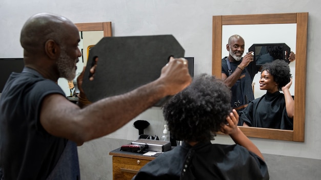 Gratis foto vrouw die haar haar laat doen in de salon door een mannelijke kapper