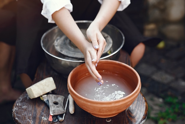 Vrouw die haar handen wast bij de aardewerkopslag