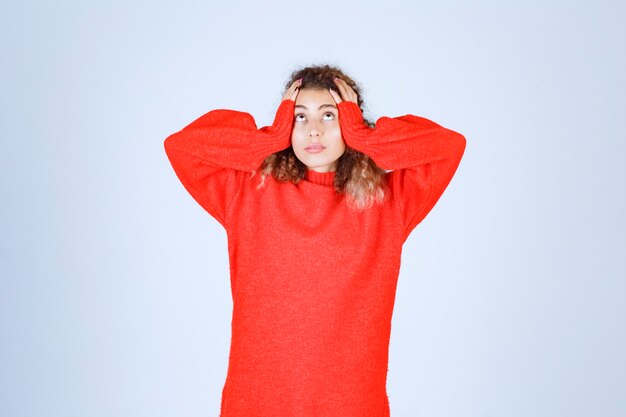 vrouw die haar hoofd met beide handen vasthoudt.