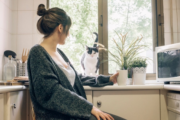 Gratis foto vrouw die haar kat in keuken bekijkt