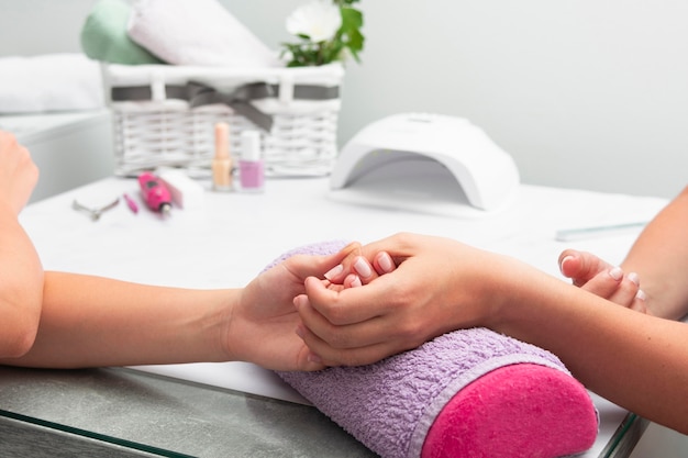 Vrouw die haar manicure heeft die bij de salon met exemplaarruimte wordt gedaan