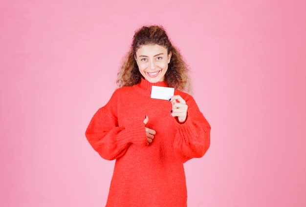 vrouw die haar nieuwe visitekaartje houdt en het teken van de plezierhand toont.