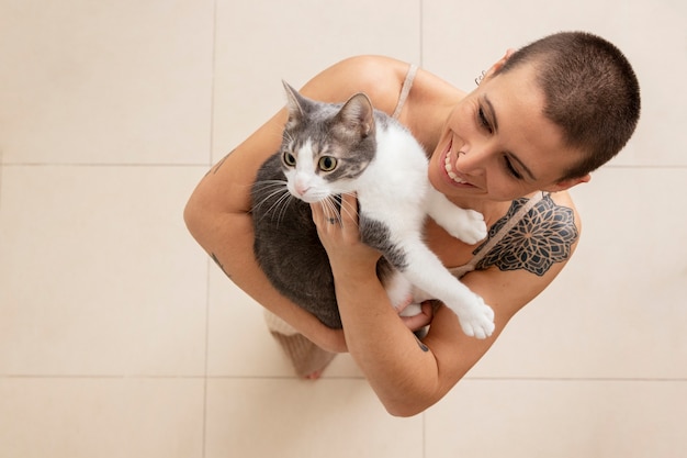 Vrouw die haar schattige kat thuis vasthoudt